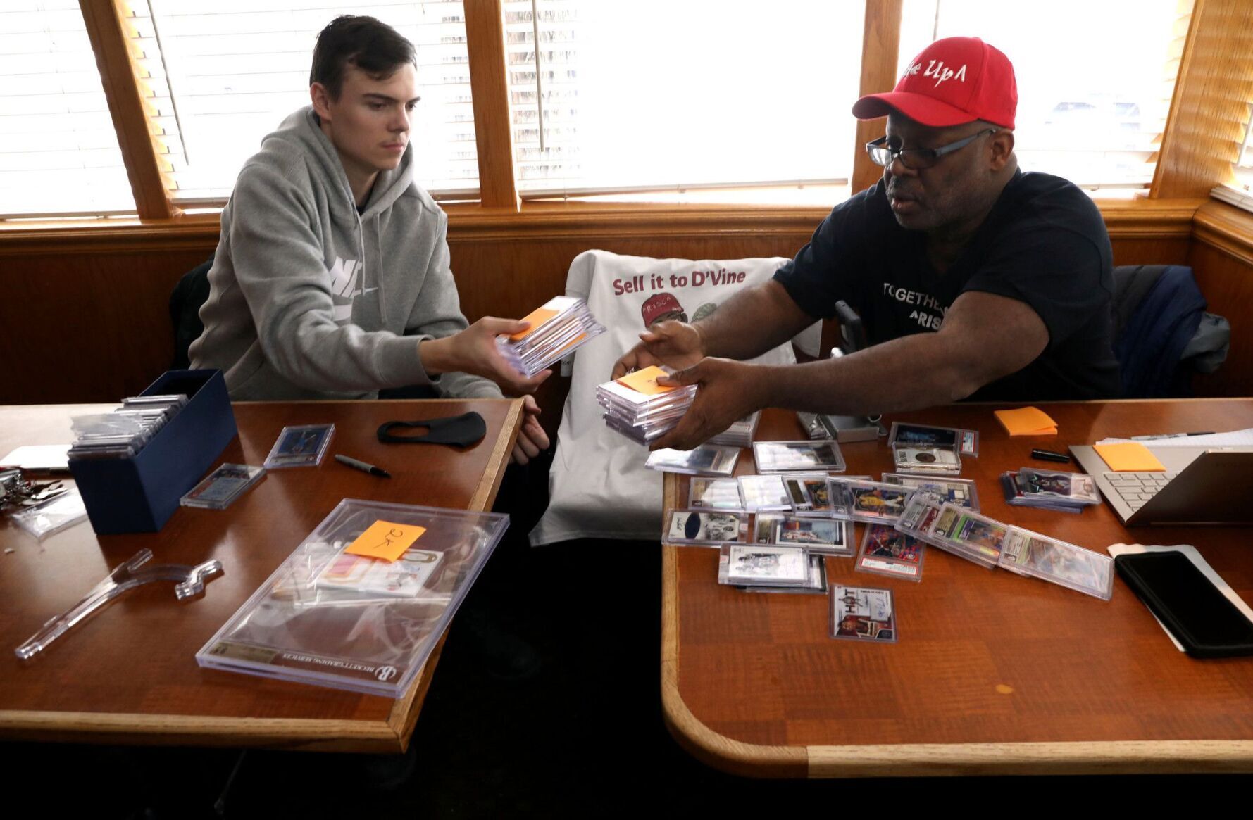 Sports card collectors Brandon Sommers, left, and Anthony Dovine select cards, haggle over prices and joke around over sports cards worth thousands at a corner table inside the Red Apple Pancake House in Carol Stream on Feb. 11, 2021.